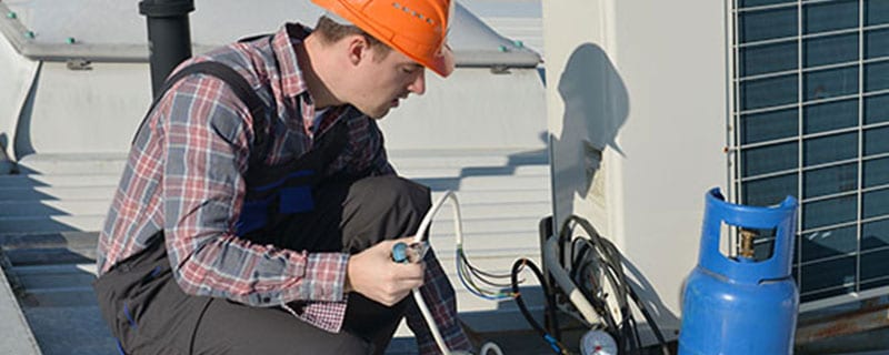 service tech adding refrigerant to commercial unit